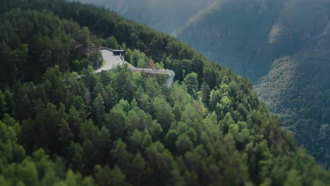 A-narrow-asphalt-road-winding-uphill-through-the-dense-forest,-leading-to-the-Stegastein-viewpoint