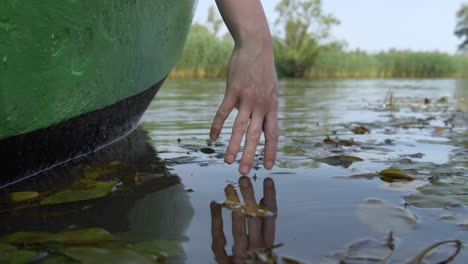 Woman-touching-the-water-with-her-hand-from-a-boat-on-a-lake-or-river