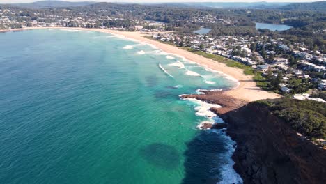 Drone-aerial-pan-footage-of-North-Avoca-beach-with-ocean-waves-headland-coastline-Central-Coast-NSW-Australia-4K