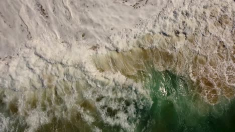 Drone-aerial-shot-of-ocean-water-splashing-onto-sand-close-up-Central-Coast-beach-NSW-Australia-4K