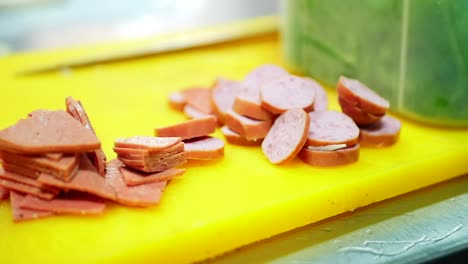 Sausages-cut-up-in-slices-on-a-yellow-cutting-board,-slider-shot
