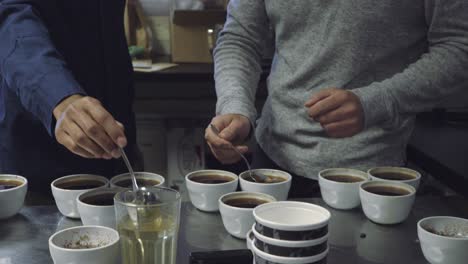 Two-men-dipping-spoons-in-cups-at-coffee-tasting-and-cupping-session