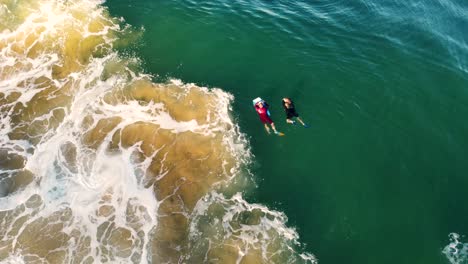 Drone-aerial-shot-of-2-bodyboarders-floating-and-waiting-in-ocean-break-sand-bar-North-Avoca-Central-Coast-NSW-Australia-4K