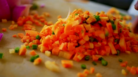 A-Person-mixing-chopped-carrots-and-peas-with-hands-on-a-wooden-cutting-board,-close-up