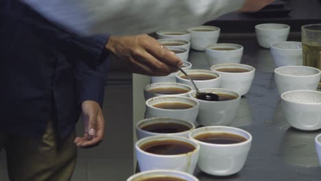 Hand-dipping-spoon-in-cup-at-coffee-tasting-and-coffee-cupping-session