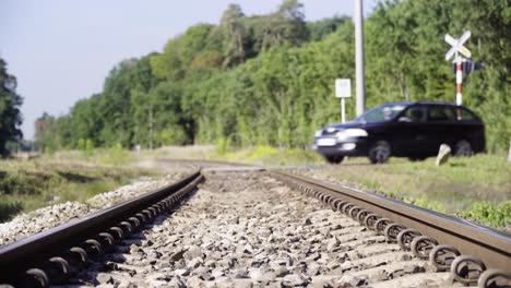 The-station-wagon-runs-through-the-railway-crossing-in-countryside-in-4K