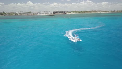 AERIAL---Luxury-boat-speeding-through-blue-waters,-Cancun,-Mexico,-spinning-shot
