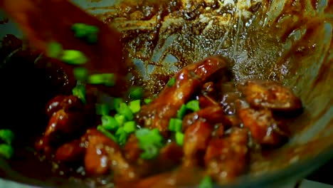 Chicken-Wings-sizzling-in-a-pan-with-green-onion-over-a-hot-stove,-static-shot