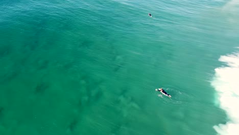 Drone-aerial-shot-of-surfer-duck-dive-Pacific-ocean-sandbar-wave-break-The-Entrance-Central-Coast-NSW-Australia-4K