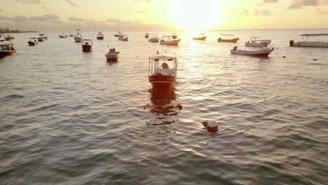 AERIAL---Boats-anchored-at-sunrise-off-the-coast-of-Cancun,-Mexico,-lowering-shot
