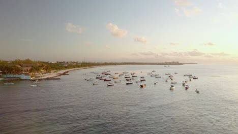 AERIAL---Boats-anchored-at-sunrise,-coast-of-Cancun,-Mexico,-wide-truck-left