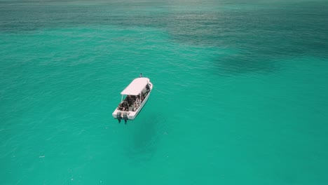 AERIAL---Tour-boat-lying-in-the-beautiful-turquoise-waters-off-of-Cancun,-Mexico