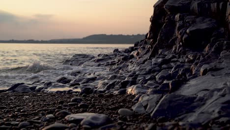 Waves-washing-over-pebble-beach-and-rocks-at-bottom-of-cliff,-Ogmore-on-Sea,-South-Wales-UK
