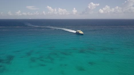 AERIAL---Luxury-yacht-speeding-through-turquoise-waters-off-of-Cancun,-Mexico