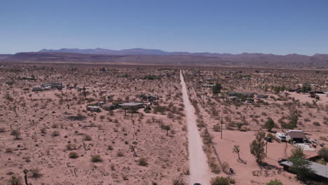 Joshua-Tree-California-car-driving-down-dirt-road-with-houses-in-desert