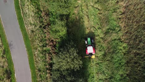 Tractor-in-field-trimming-hedges,-aerial-view-overhead-tracking-shot