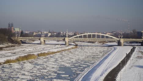 Frozen-river-with-ice-floes-with-a-bridge-and-the-city-in-the-background-1