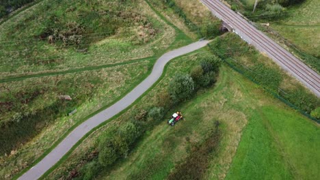 Tractor-in-field-driving-along-track,-aerial-shot-distant-view