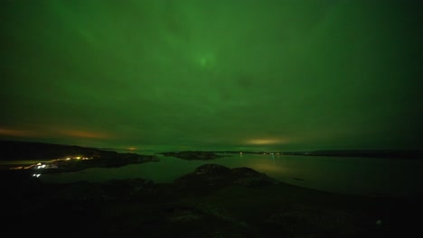 Clouds-brightly-lit-by-the-northern-lights-pass-above-the-fjord