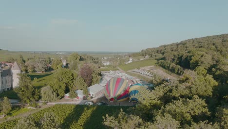 4k-Antenne-Zwei-Heißluftballons,-Die-Sich-Aufblasen,-Umgeben-Von-Alten-Düsenjägern-Und-Schloss