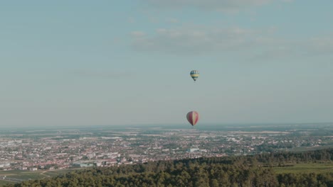 4k-Heißluftballons-Aus-Der-Luft-Mit-Stadt-Im-Hintergrund-Drohnen-LKW-Von-Rechts-Nach-Links