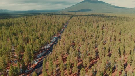 4k-Aerial-country-road-surrounded-by-evergreens-and-mount-in-the-back-Drone-overhead-truck-left