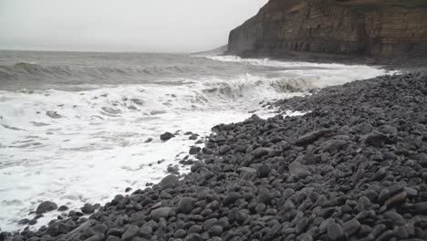 Winter-Tide-splashing-in-over-rocky-beach-at-Dunraven-Bay,-South-Wales