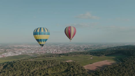 4k-Aerial-two-hot-air-balloons-above-vineyards-with-city-in-background