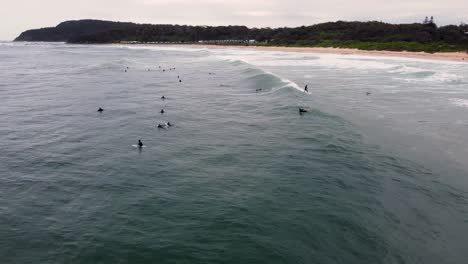 Drone-pan-shot-of-big-group-of-surfers-in-rainy-Shelly-Beach-The-Entrance-Central-Coast-NSW-Australia-4K