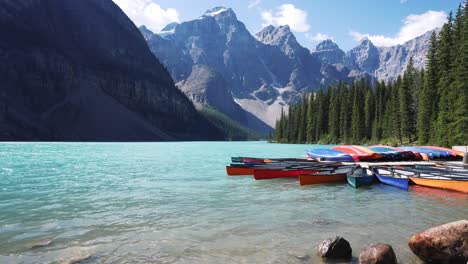 Crystal-clear-blue-water-at-Moraine-Lake-with-canoes-and-a-mountain-backdrop