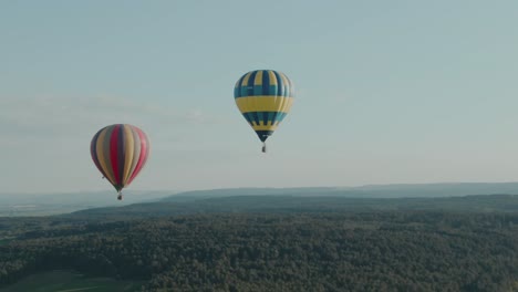 4k-Aerial-two-hot-air-balloons-flying-over-the-forest-on-a-beautiful-day