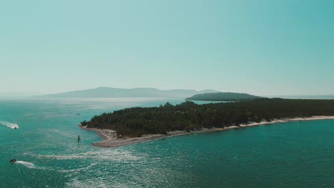 4k-Aerial-small-island-with-mountains-in-background-and-boat-around