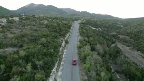 AERIAL---Car-driving-down-a-hill-road,-Tamaulipas,-Mexico,-wide-forward-shot