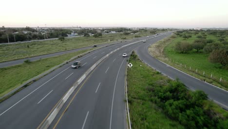 AERIAL---Vert-light-traffic-on-a-highway-in-Reynosa,-Mexico,-wide-tracking-shot
