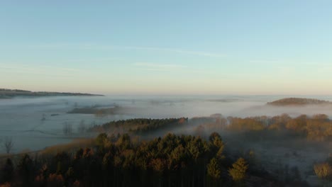 Drohnenaufstieg-Enthüllt-Eine-Decke-Aus-Tief-Hängendem-Nebel,-Die-Auf-Feldern-In-Der-Britischen-Landschaft-Sitzt