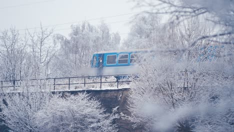A-small-two-carriage-local-train-passes-on-the-bridge-through-the-snowy-winter-landscape
