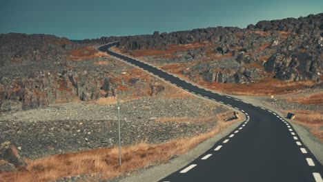 A-narrow-asphalt-road-leading-through-the-desolate-tundra-landscape