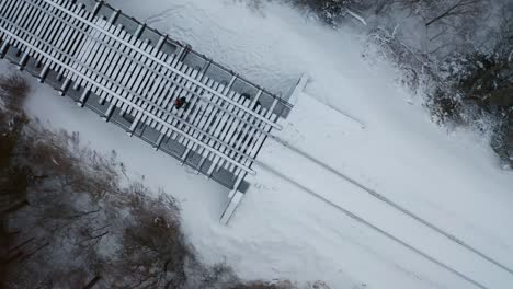 Observed-from-above,-a-man-walks-along-a-snow-covered-railway-track