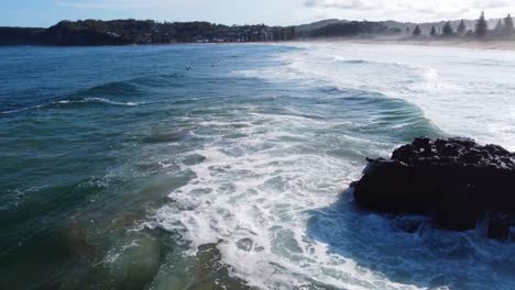 Luftdrohnenlandschaftsansicht-Des-Surferkletterns,-Der-Von-Felsen-In-Wellen-Springt,-Pazifischer-Ozean,-North-Avoca,-NSW,-Zentrale-Küste-4k