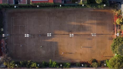 Top-Down-Shot-of-Five-Clay-Tennis-Courts-with-Players-Practicing-in-the-Morning-in-Mexico-City