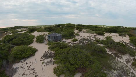 FPV-Drone-shot-of-Dune-shack-on-a-warm-summer-day-at-end-of-Dune-Shack-Trail-in-Provincetown,-Cape-Cod,-Massachusetts