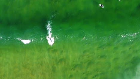 Aerial-drone-footage-bird's-eye-view-of-surfer-riding-wave-on-crystal-clear-sandbank-Avoca-Central-Coast-NSW-Australia-4K