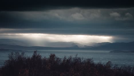 Sun-rays-pierce-the-thick-menacing-cloud-cover-above-the-fjord-lighting-the-waters-below