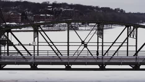 Silhouetted-against-fresh-white-snow,-a-man-walks-across-the-Arcola-high-bridge-in-Stillwater,-Minnesota
