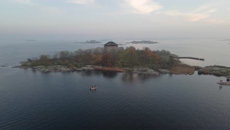 Vista-Aérea-Sobre-Dos-Pescadores-Parados-En-Su-Bote-Tratando-De-Pescar-En-El-Hermoso-Archipiélago-En-La-Ciudad-Naval-De-Karlskrona,-Suecia-1