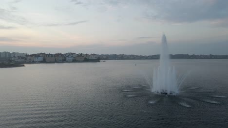 Footage-of-the-beautiful-fountain-standing-in-the-middle-of-the-water-in-the-naval-city-of-Karlskrona,-Sweden-on-a-cloudy-day-when-the-sun-is-about-to-set