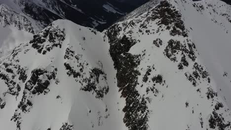 Skiers-climbing-up-a-couloir-in-the-mountains-of-British-Columbia,-Canada