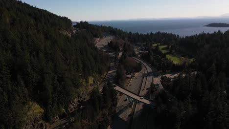 Traffic-on-the-Sea-to-Sky-highway-with-the-ocean-in-the-background-in-British-Columbia,-Canada