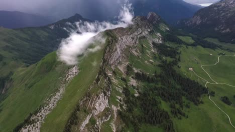 Cinematic-aerial-view-of-a-mountain-ridge-with-clouds-forming-in-the-French-Alps