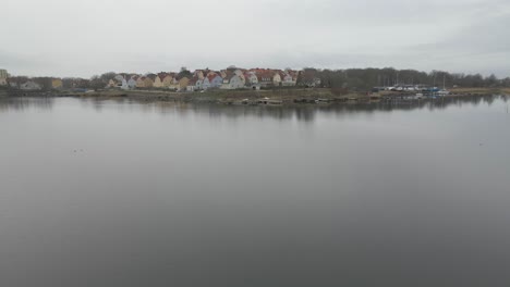 Volando-Un-Dron-Sobre-El-Agua-Tranquila-Y-Tranquila-En-Karlskrona,-Suecia,-Con-Vistas-A-Las-Hermosas-Casas-Suecas-En-Salto-En-El-Fondo